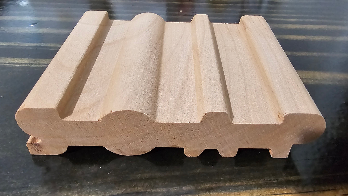 A light natural wood soap holder with a wavy, ribbed profile, displayed on a dark, reflective surface.