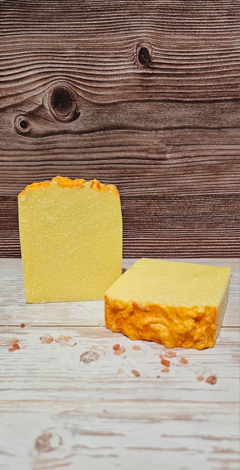 Two yellow soap bars on a wooden surface with a wooden background
