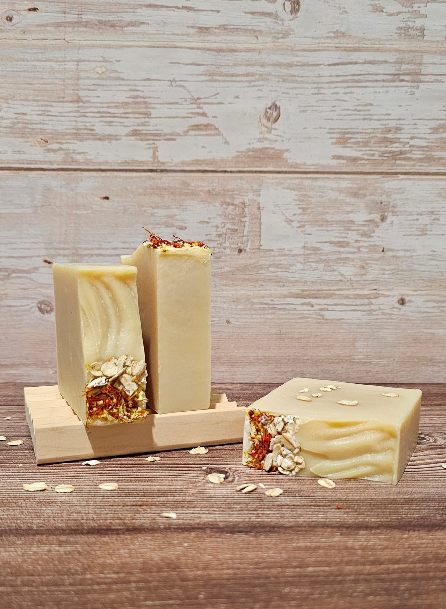 Three bars of soap with visible ingredients on a wooden surface