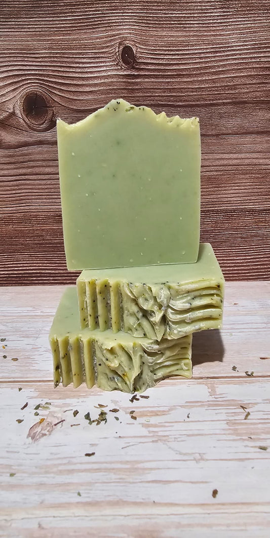 Two green soap bars stacked on a wooden surface with a wooden background