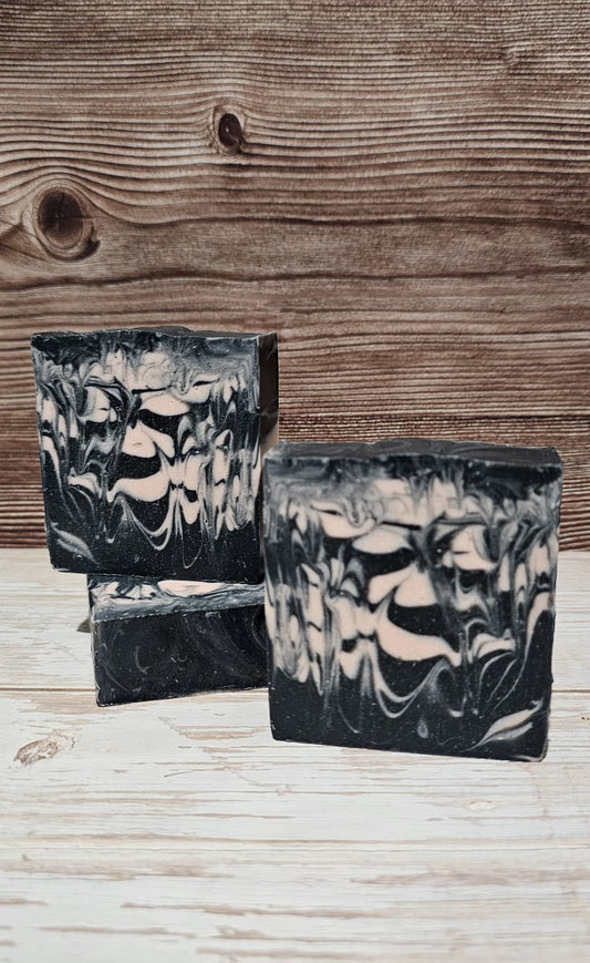 Black and pink marbled soap bars on a wooden surface