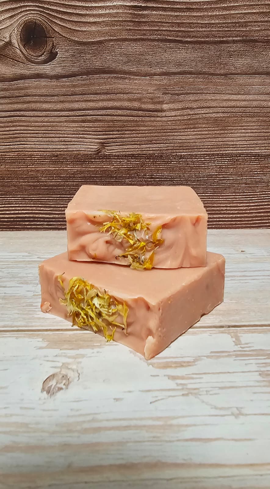 Two bars of soap with gold leaf on a wooden surface