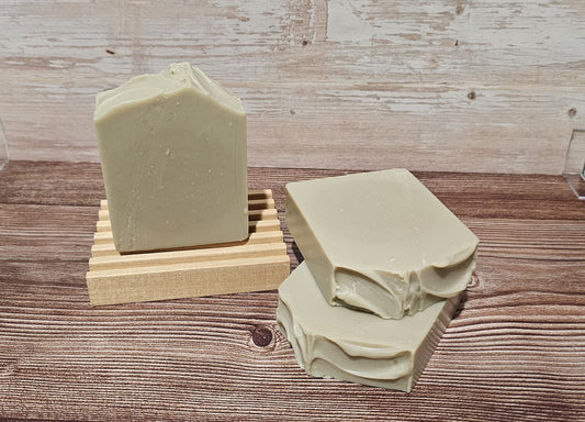Three bars of green soap on a wooden surface with a soap dish.