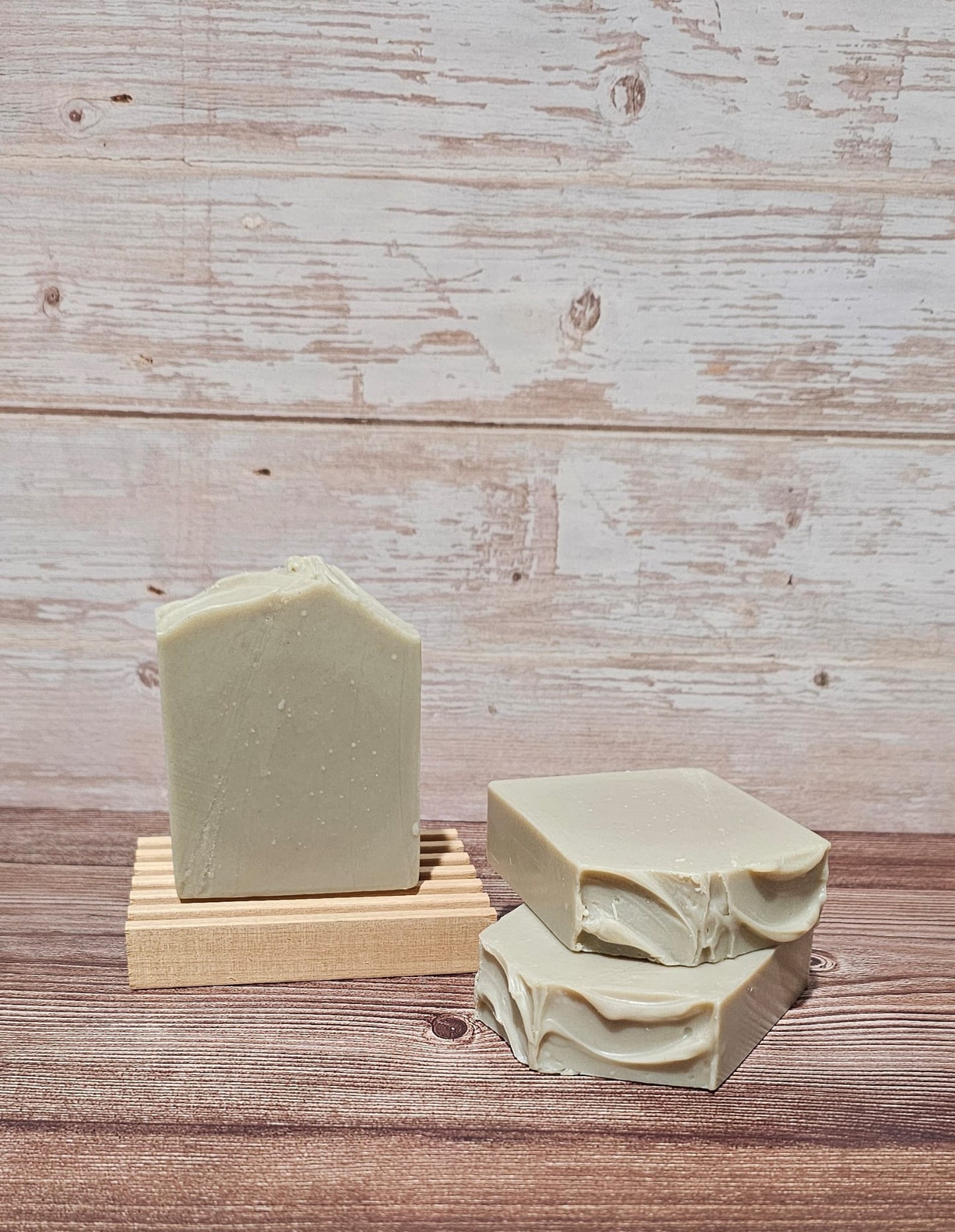 Two bars of soap on a wooden stand and two additional bars of soap on a wooden surface.