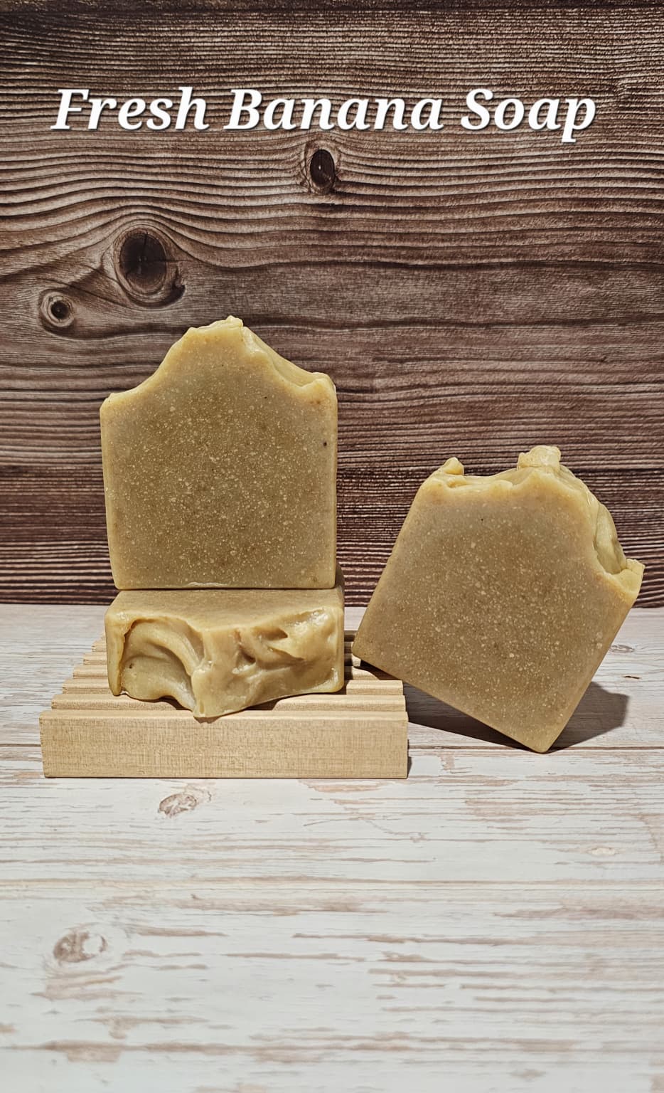 Two bars of fresh banana soap on a wooden stand with a wooden background.
