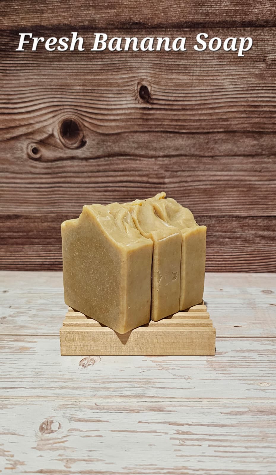 Two bars of Fresh Banana Soap on a wooden stand with a wooden background.
