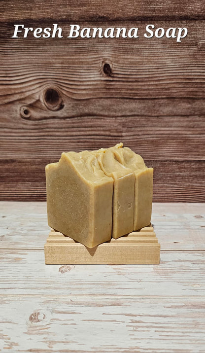 Two bars of Fresh Banana Soap on a wooden stand with a wooden background.