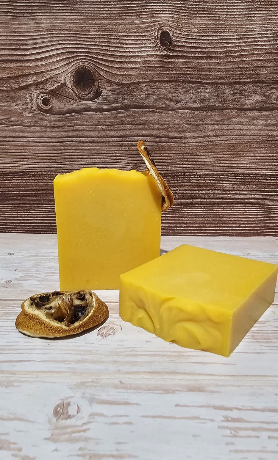 Two yellow soap bars on a wooden surface with a wooden background