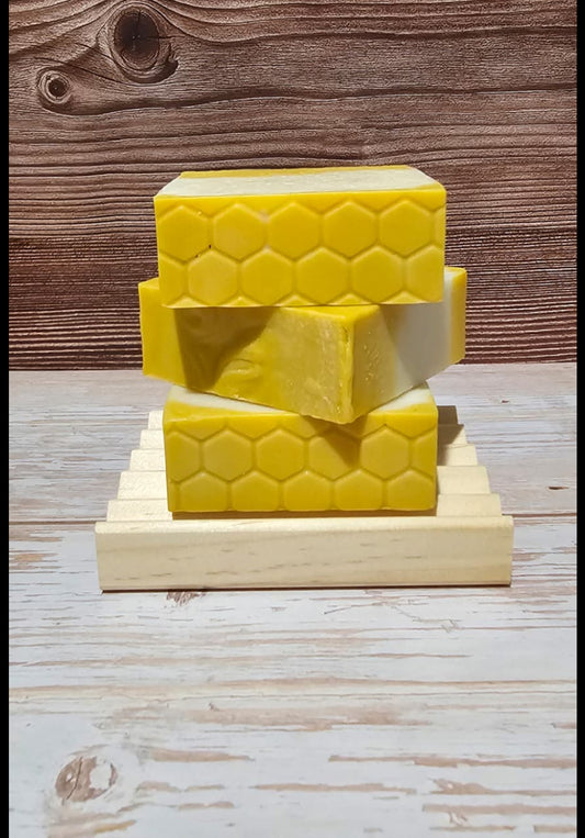Three yellow honeycomb-shaped soap bars on a wooden stand with 'Honey Bee Soap' text above.