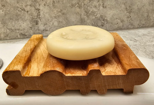 Bar of soap on a wooden soap dish with a concrete wall background