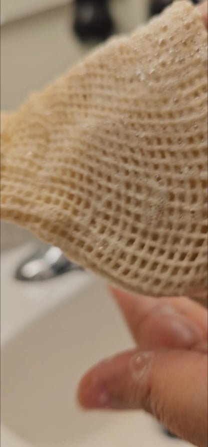 Close-up of a textured beige mesh bag held by a hand with a blurred background.