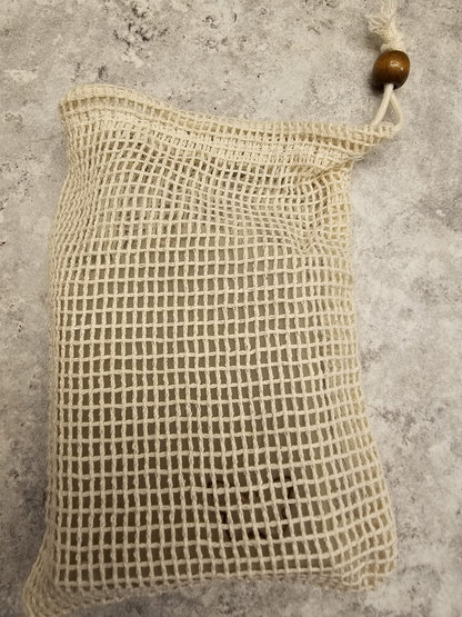 Textured beige soap bag with wooden bead on a gray surface