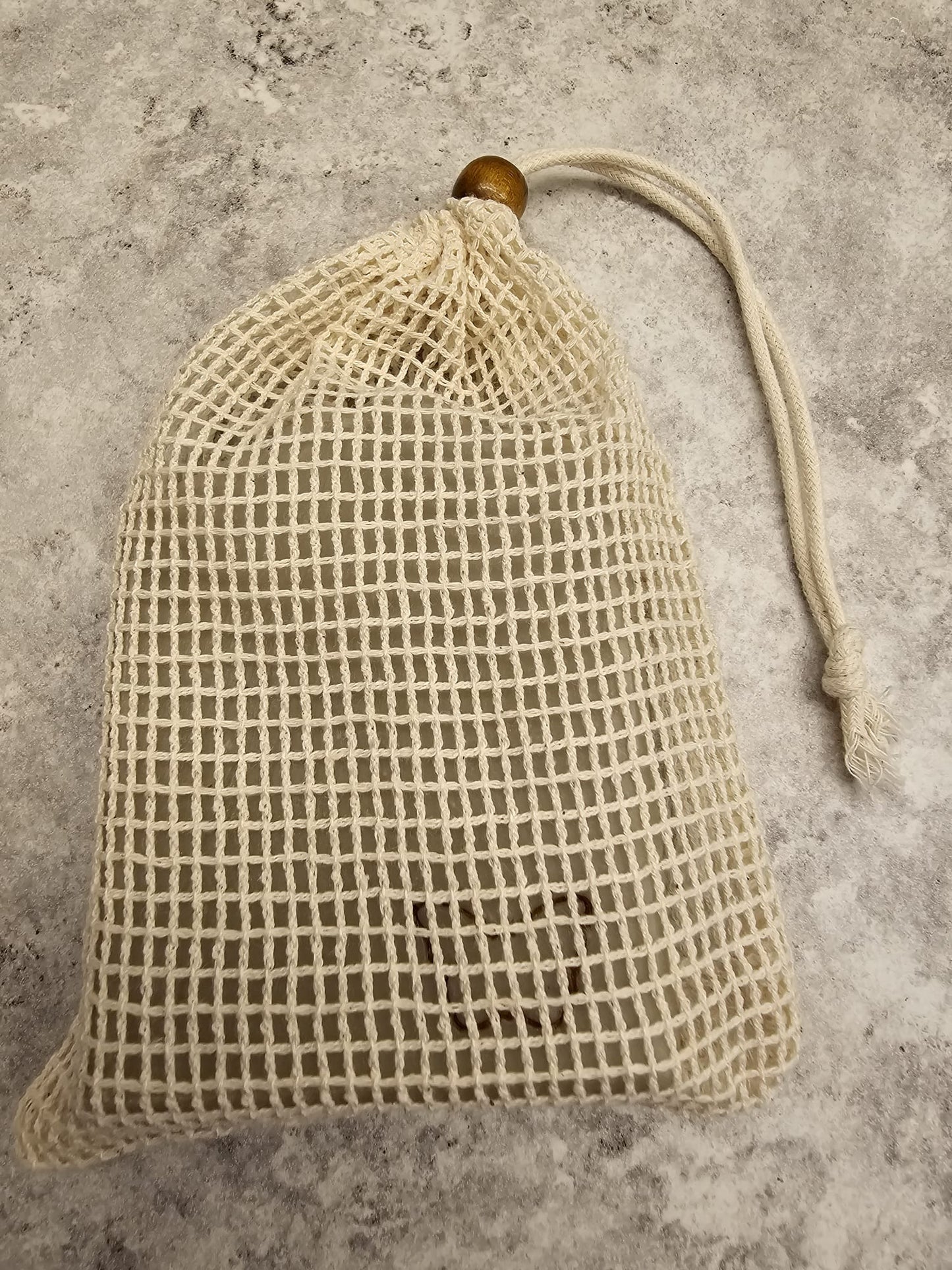 Textured beige soap bag with wooden bead on a gray surface