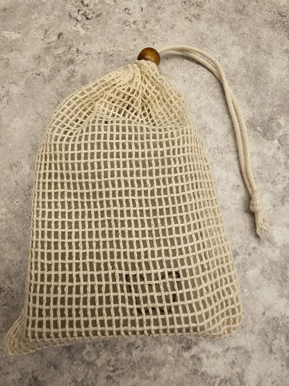 Textured beige soap bag with wooden bead on a gray surface