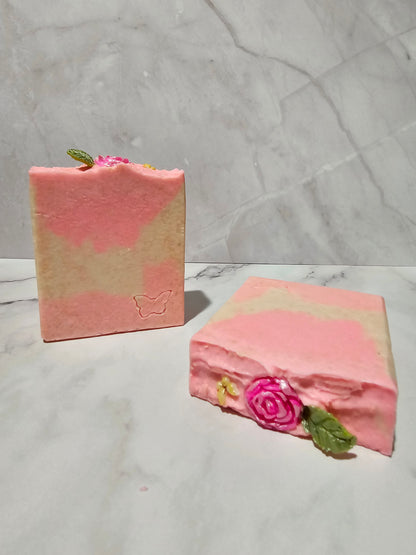 Two pink decorative boxes with floral designs on a marble surface
